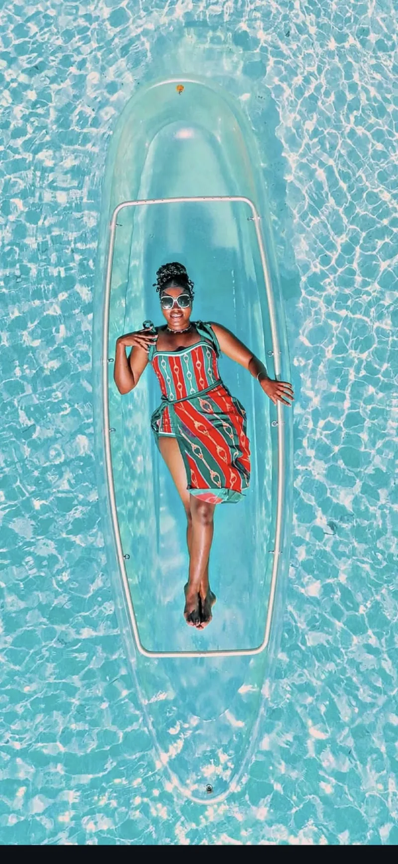A woman reclining in a glass-bottom kayak on Zanzibar's turquoise water