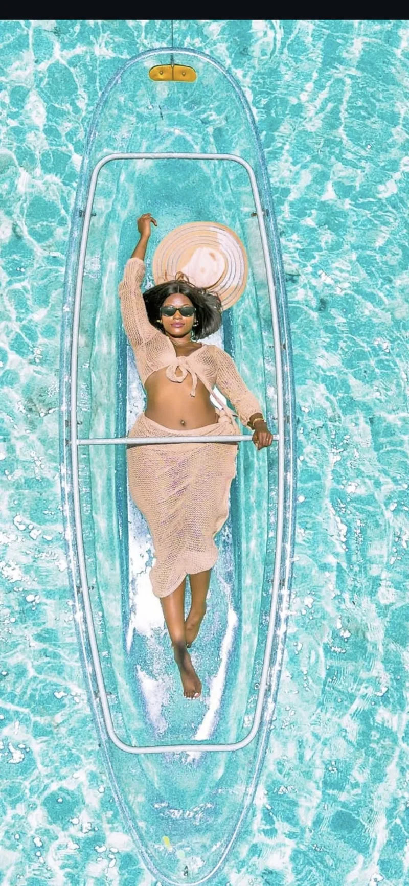 A woman relaxing in a glass-bottom kayak on the turquoise water off Zanzibar